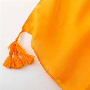 Detailed macro view of bright orange scarf with decorative tassel trim and fine weave texture