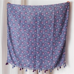 Detail view of light linen scarf featuring colorful owl patterns and purple fringe tassels