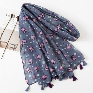 Detail of owl pattern cotton linen scarf with soft tassels and artistic magazine backdrop