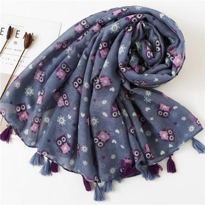 Detail of blue cotton linen scarf featuring purple owl prints and soft colorful tassels