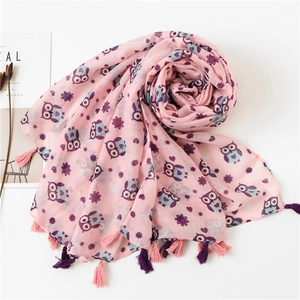 Close-up of light pink linen scarf featuring owl prints and soft colorful tassels