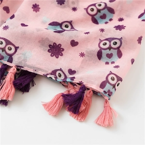 Detailed macro view of the owl print pattern and handmade tassel fringe on a pink scarf