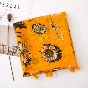 Dettaglio di sciarpa in cotone giallo a fiori con margherite bianche e frange