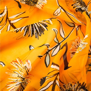 Dettaglio di sciarpa leggera in cotone arancione con stampa di girasoli bianchi