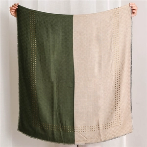 Detail of two-tone scarf showing dark green and beige fabric with gold rivet accents