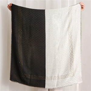 Detail of bicolored cotton linen shawl with gold studs and frayed edges on black and white fabric