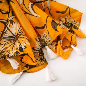 Dettaglio di sciarpa in cotone giallo con stampe di margherite bianche e nappe lunghe
