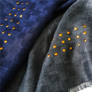 Detail of linen scarf showing checkerboard texture and golden metal rivets decorations