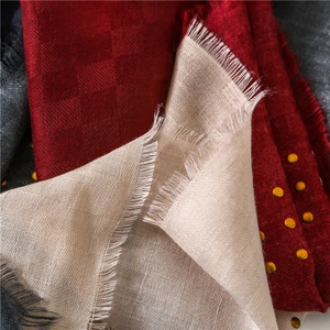 Detail of red checkered scarf with golden studs and handcrafted fringe textures