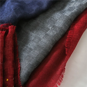 Detail view of cotton linen scarf texture with studded metal trim and fringed edges