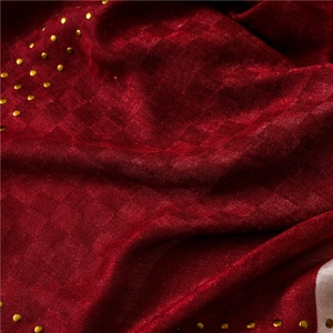 Detail of dark red linen scarf featuring jacquard texture and golden rivet studs