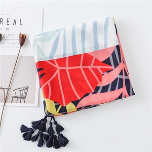 Detail of floral linen scarf with tropical leaf pattern and navy tassel trim fringe