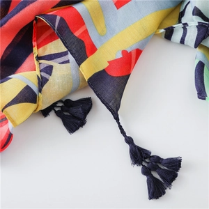 Detailed close-up of colorful floral linen scarf featuring artisanal blue tassel charms