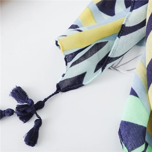 Close-up of lightweight floral scarf showing geometric print and navy tassel edges