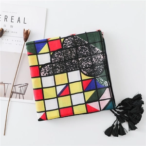 Detail of colorful geometric pattern scarf featuring long black fringe and tassels