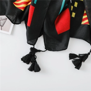 Close-up of black ethnic scarf with colorful geometric patterns and braided fringe tassels