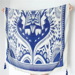Châle géométrique bleu et blanc avec motifs floraux et finitions à pompons bleus