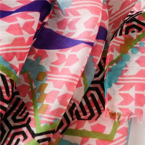 Detail of pink geometric pattern silk scarf showing soft fabric texture and frayed edges