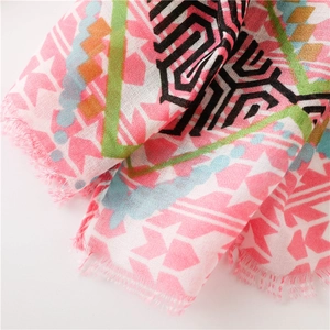Detailed close-up of pink geometric silk scarf fabric with frayed fringe and tassels