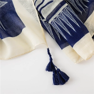 Détail d'une écharpe géométrique bleu marine et beige avec texture lin et franges