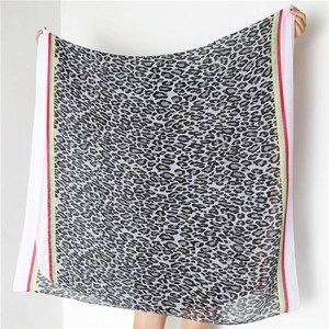Detail of grey leopard print scarf with colorful striped edges and soft cotton texture