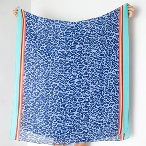 Detail of pleated leopard print scarf with colorful striped edges in blue and orange