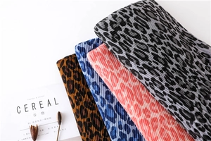 Detailed view of pleated leopard print scarves in brown, blue, pink and grey colors