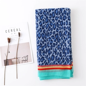 Detail of blue leopard print pleated scarf with vibrant striped edge on white background