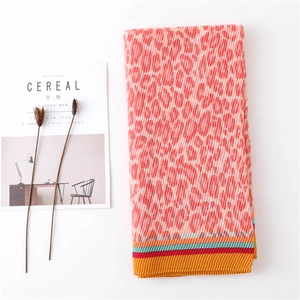 Detail of coral orange leopard print scarf with pleated texture and striped hem edges
