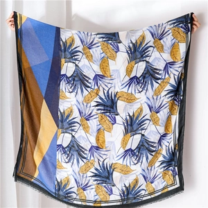 Detailed view of wide lightweight shawl with colorful floral botanical print and geometric trim