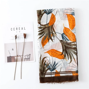 Detail of tropical plant print shawl with brown tassel fringe and soft cotton texture