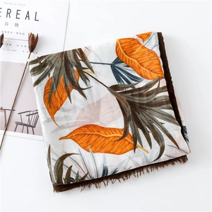 Detailed flat lay of tropical leaf print scarf with tassels beside Cereal magazine