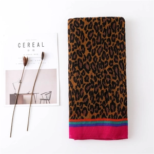 Macro shot of pleated leopard print scarf with colorful striped edge and magazine prop