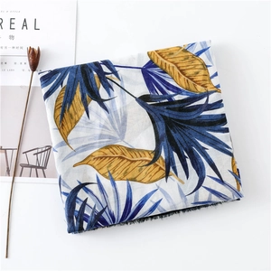 Detail view of tropical leaf print scarf with navy and yellow tones and fringe edges