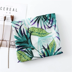 Flat lay of thin tropical leaf print scarf with raw edges and aesthetic magazines