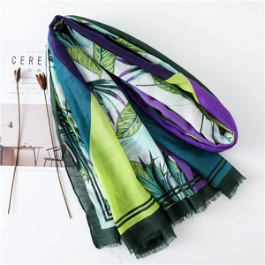 Detail of tropical green leaf pattern shawl with raw fringe edges on white background