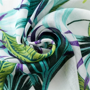 Close-up detail of tropical leaf print fabric with vibrant green and purple palm texture