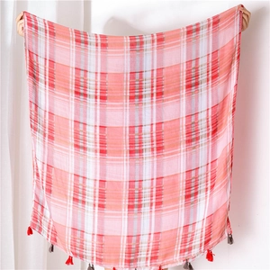 Detail of red and white plaid cotton linen shawl featuring delicate fringed tassel edges