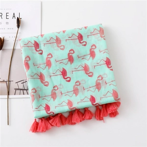 Detail of mint green flamingo print scarf featuring pink tassel fringe and soft cotton texture