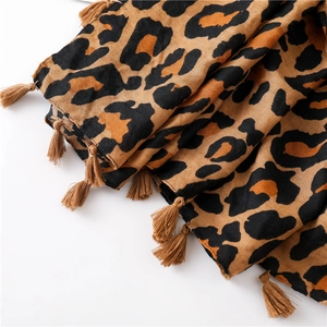 Close-up of leopard print scarf fabric showing brown fringe tassels and woven texture