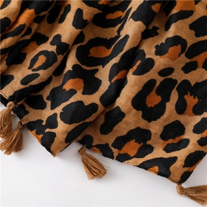 Detailed close-up of brown leopard print scarf fabric and delicate fringe tassel edges