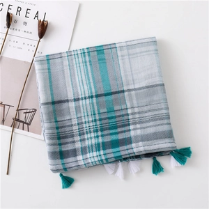 Detail of plaid scarf featuring blue and grey patterns with handmade two-tone tassels