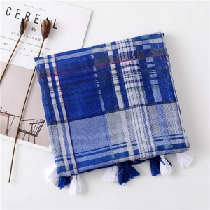 Close-up of blue and white plaid scarf featuring decorative fringe and a lifestyle setting