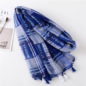 Detail of blue and white plaid scarf with fringe tassels on white background