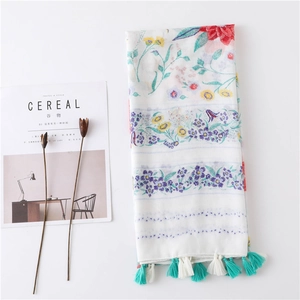 Écharpe longue bohème à fleurs et glands sur fond blanc avec accessoires décoratifs