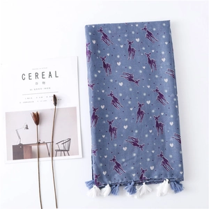 Detailed view of blue scarf with deer print and hand-knotted tassels on white background