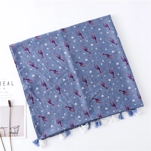 Detail of blue scarf featuring purple deer prints and decorative bicolor fringe tassels