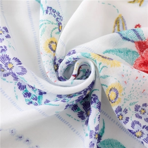 Gros plan sur le tissu doux d'une écharpe bohème avec fleurs violettes et franges
