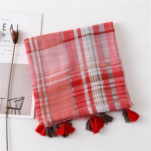 Close-up of red and grey plaid scarf with fringe details and soft woven texture