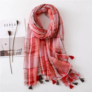Detailed close-up of pink plaid cotton scarf with soft fringe edges on white background